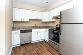 Located at 495 Coachman Dr in Troy, Michigan, this single-floor residence offers a well-organized and practical layout suited for comfortable everyday living. The kitchen is equipped with rich, warm-toned wood cabinetry, granite-style laminate countertops, white appliances including a refrigerator, electric range, and dishwasher, and durable hardwood-style flooring. Natural light filters in through vertical-blind-covered windows, and a ceiling fan with a wall-mounted air conditioning unit provides climate control in the adjoining dining or living area, which also features baseboard heating. The living spaces are generously proportioned, with plush neutral carpeting and clean white walls that create a bright, open feel. Windows throughout the unit bring in views of the surrounding greenery, adding a sense of connection to the outdoors. The bedroom offers a comfortable, carpet-floored retreat with a dedicated closet featuring built-in shelving. The full bathroom is finished with tile wainscoting, a soaking tub, a separate shower, hardwood-style flooring, and a wood vanity topped with a granite-style countertop and a well-lit mirror. Baseboard heating is found throughout the unit, ensuring consistent warmth during Michigan winters.