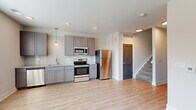 This two-story residence at 800 E Long Street in Columbus, Ohio offers a well-designed layout across two floors, with the main living areas on the ground floor and bedrooms above. The first floor, the larger of the two levels, houses the kitchen, living room, and one bathroom. The kitchen is outfitted with gray shaker-style cabinetry, a white subway tile backsplash, stainless steel appliances including a refrigerator, range, microwave, and dishwasher, and pendant lighting over light wood-style flooring. The open adjacent living area benefits from multiple windows that bring in natural light. A sliding barn door adds a modern design detail near the entry hallway.

Upstairs, two bedrooms feature neutral carpet and light-toned walls, creating a calm atmosphere. The primary bedroom is a comfortable size and provides access to a dedicated closet with wire shelving and a stacked washer and dryer unit. Both bathrooms are finished with gray vanity cabinetry and granite-style countertops. Throughout, light wood-style flooring, recessed lighting, and a clean, neutral color palette create a cohesive, contemporary feel.
