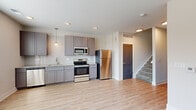 This two-story residence at 800 E Long Street in Columbus, Ohio offers a well-designed layout across two floors, with the main living areas on the ground floor and bedrooms above. The first floor, the larger of the two levels, houses the kitchen, living room, and one bathroom. The kitchen is outfitted with gray shaker-style cabinetry, a white subway tile backsplash, stainless steel appliances including a refrigerator, range, microwave, and dishwasher, and pendant lighting over light wood-style flooring. The open adjacent living area benefits from multiple windows that bring in natural light. A sliding barn door adds a modern design detail near the entry hallway.

Upstairs, two bedrooms feature neutral carpet and light-toned walls, creating a calm atmosphere. The primary bedroom is a comfortable size and provides access to a dedicated closet with wire shelving and a stacked washer and dryer unit. Both bathrooms are finished with gray vanity cabinetry and granite-style countertops. Throughout, light wood-style flooring, recessed lighting, and a clean, neutral color palette create a cohesive, contemporary feel.