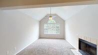 This thoughtfully renovated 1-bedroom, 1-bathroom residence offers a well-designed single-floor layout that maximizes both comfort and functionality. The living area makes a strong impression with its soaring vaulted ceiling, plush carpeting, and a tile-surround fireplace that anchors the room as a warm focal point. Pendant lighting illuminates the transition into the kitchen area, which features wood-look flooring throughout.

The renovated kitchen is a standout, showcasing stainless steel appliances — including a range, microwave, and refrigerator — paired with white cabinetry, a stone tile backsplash, and dark countertops. A peninsula with an integrated sink and pendant lights above provides both prep space and a casual dining area.

The spacious bedroom is highlighted by dramatic vaulted ceilings, a ceiling fan, and an arched window that floods the room with natural light and outdoor views. Soft carpeting and a generous walk-in closet add to the room's comfort and practicality.

The full bathroom is clean and efficient, featuring tile flooring, a tub/shower combination with white subway tile surround, and built-in cabinetry for additional storage. Throughout the residence, neutral tones and updated finishes create a bright, move-in-ready atmosphere.