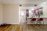 Located at 1160 Morse Ave in Sunnyvale, CA, this one-bedroom, one-bathroom residence offers a well-designed single-level layout that maximizes functionality and comfort. The open-concept living and kitchen area serves as the heart of the home, featuring rich dark wood cabinetry, stainless steel appliances including a range and microwave, and a mosaic tile backsplash that adds a stylish accent. A peninsula with a white countertop and bar seating for two provides a casual dining option and connects the kitchen seamlessly to the living area. Light wood-style flooring runs throughout the main living spaces, contributing to a bright and cohesive aesthetic. Large windows in the living area frame views of the landscaped courtyard, filling the space with natural light. The bedroom offers plush carpeting and a window overlooking lush greenery, creating a peaceful retreat. A generously sized walk-in closet with multi-tiered shelving and hanging rods provides ample storage. The bathroom includes built-in shelving for additional organization and a large mirror above the vanity. Neutral wall tones throughout the residence create a clean and versatile backdrop, making the space feel open and inviting.