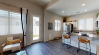 This single-floor residence offers a thoughtfully designed open-concept layout that seamlessly connects the living, dining, and kitchen areas. The living room features elevated ceilings, warm neutral-toned walls, and durable wood-look flooring that flows throughout the entire unit. Natural light pours in through multiple windows dressed with clean white blinds and navy accent curtains, creating a bright and welcoming atmosphere. A glass-panel door in the living area provides direct access to a private outdoor patio, enhancing the connection between interior and exterior spaces.

The kitchen is a standout feature, equipped with crisp white shaker-style cabinetry, granite countertops, and a full suite of stainless steel appliances including a refrigerator, electric range with over-the-range microwave, and dishwasher. A peninsula with bar seating adds functional counter space and encourages casual dining.

The bedroom is a serene retreat highlighted by a large window with outdoor views, rich dark wood-look flooring, and ample space for full-sized furniture. The bathroom is efficiently laid out with white cabinetry, granite countertops, wood-look flooring, and a window that introduces natural light. The overall design balances modern finishes with a clean, comfortable aesthetic.