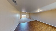 This single-floor home offers a well-designed layout with a variety of notable architectural features throughout. The expansive living area immediately draws attention with its dramatic vaulted ceiling adorned with exposed wood beams, a ceiling fan, and a seamless transition between rich hardwood flooring and plush carpet. A sliding glass door floods the space with natural light and provides direct access to an outdoor patio area, offering views of the surrounding neighborhood.

The kitchen is efficiently arranged in a U-shape configuration, featuring light wood cabinetry, granite-style countertops, and a full suite of stainless steel appliances including a refrigerator, dishwasher, electric range, and built-in microwave. A window above the sink brings in additional natural light.

The bedrooms are generously sized and finished with soft wall-to-wall carpeting. The primary bedroom includes a ceiling fan and a full-width mirrored sliding closet, adding both functionality and a sense of depth to the room. Additional bedrooms share a similar warm, neutral palette and are equally comfortable in scale.

The bathroom presents a clean, practical design with wood-look flooring, a single-sink vanity with warm-toned cabinetry, a large mirror, and access to a dedicated laundry and storage room. Ceiling fans are present throughout the home, contributing to year-round comfort.