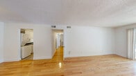 Located at 2101 Gorman St in Raleigh, NC, this single-floor, 2-bedroom, 2-bathroom home offers a clean and functional layout with consistent design choices throughout. Warm hardwood flooring flows through the living areas, hallway, and bedrooms, creating a cohesive and inviting atmosphere. The spacious living room is a standout, featuring a distinctive white-painted brick accent wall that adds texture and character, a tiled entryway at the front door, and a sliding glass door that floods the room with natural light and provides access to an outdoor area with views of the surrounding neighborhood. The kitchen is efficiently designed with white cabinetry, dark countertops, a double-basin sink, and white appliances including a range and refrigerator, all set atop tile flooring. Both bedrooms are bright and well-proportioned, each featuring hardwood floors, windows with natural light, and closet space—the primary bedroom offering a notably generous footprint. The bathrooms are clean and simply appointed, with one featuring a framed mirror, white vanity, and chrome fixtures. Throughout the home, textured ceilings and crisp white walls create a bright, neutral backdrop. With five closets distributed across the floor plan, this home provides ample storage.