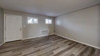 Located at 3900 N Shadeland Ave in Indianapolis, Indiana, this one-bedroom, one-bathroom unit offers a practical and well-designed single-floor layout. Throughout the space, neutral gray walls and contemporary wood-look luxury vinyl plank flooring create a clean, cohesive aesthetic that ties each room together.

The living area is open and functional, providing a comfortable space for daily living. Adjoining the living area is a compact kitchen outfitted with white cabinetry, open shelving, a white electric range, and a sink with countertop workspace arranged in an efficient L-shaped configuration — ideal for everyday meal preparation.

The living room area features two horizontally-oriented windows that allow natural light to filter in, complemented by a wall-mounted HVAC unit for climate control. The bedroom is a well-proportioned private retreat, benefiting from a large window that brings in additional natural light and an adjoining closet for dedicated storage.

The bathroom is clean and straightforward, featuring a tiled shower/tub combo, a toilet, and matching LVP flooring that continues the consistent design language of the rest of the unit. Textured ceilings appear throughout, adding a subtle layer of detail to the overall interior. This unit offers a straightforward, move-in-ready layout well-suited for individuals or couples seeking comfortable living in Indianapolis.