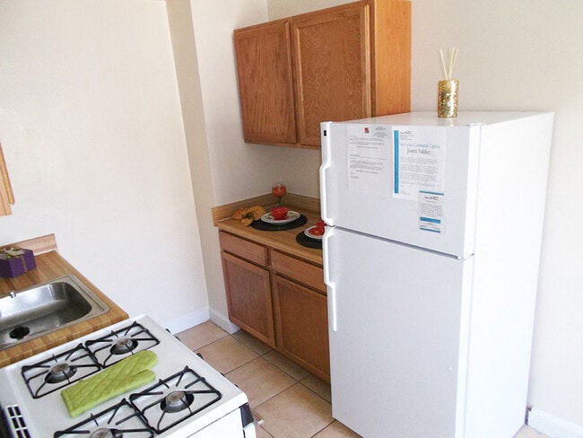 Galley Kitchen With White Appliances - Oaklawn Apartments