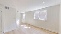 Located at 7900-7922 Fairfield St in Philadelphia, PA, this one-bedroom, one-bathroom unit offers a thoughtfully designed layout with modern finishes throughout. The main living area is bright and open, featuring light-toned hardwood flooring that runs seamlessly through the space, complemented by crisp white walls and recessed lighting that keep the ambiance clean and contemporary. Multiple windows allow natural light to pour in, with views of the surrounding neighborhood adding a sense of connection to the outdoors. A louvered closet door adds a classic touch while maximizing storage. The spacious bedroom continues the same hardwood flooring and neutral palette, with a large window framing outdoor greenery and filling the room with abundant sunlight. Recessed ceiling lights provide consistent illumination throughout. The bathroom is finished with large-format, light gray tile extending from floor to wall, creating a sleek and cohesive look. A soaking tub with a white surround and a modern vanity with a wood-tone base complete the space. Overall, the unit presents a fresh, move-in-ready feel with clean lines, quality finishes, and a bright, airy atmosphere ideal for comfortable everyday living.