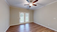 Located at 156 Millstone Rd in Florence, SC, this single-story, 2-bedroom, 2-bathroom home offers a well-designed layout with consistent wood-look flooring throughout. The open-concept living, dining, and kitchen area forms the heart of the home, where a peninsula kitchen counter with granite-style surfaces and warm wood cabinetry flows seamlessly into the dining area—accented by an elegant chandelier—and onward to the spacious living room. The living room is highlighted by a ceiling fan with light fixture, crown molding, a textured ceiling, and a set of French doors that fill the space with natural light and provide outdoor access. The kitchen is efficiently designed with ample cabinetry on both sides, matching countertops, a built-in microwave, and an electric range. A hallway leads to both bedrooms and bathrooms. The generously sized primary bedroom includes a ceiling fan and an en-suite bathroom featuring a tub/shower combo, wood-toned vanity, and hardwood-style flooring. The second bedroom is well-proportioned with its own closet. Three closets throughout the home—including a spacious walk-in with wire shelving—offer abundant storage. A dedicated laundry room adds everyday convenience to this thoughtfully appointed home.
