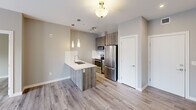 Located at 11235 105 Ave NW in Edmonton, Alberta, this thoughtfully designed 2-bedroom, 2-bathroom unit offers a functional and modern living experience across a single floor. The open-concept living, dining, and kitchen area forms the heart of the space, finished with light-toned hardwood flooring and neutral grey walls that create a clean, contemporary aesthetic. The kitchen is a standout feature, equipped with stainless steel appliances including a refrigerator, stove, and built-in microwave, complemented by wood-toned cabinetry, a white quartz peninsula with an undermount sink, a subway tile backsplash, and stylish pendant lighting. A large window in the living area allows natural light to fill the space, offering views of the surrounding neighbourhood. Both bedrooms are comfortably sized with hardwood flooring, neutral walls, and ample closet space. The primary bedroom includes a dedicated closet, while a second bedroom features a window with natural light. Two full bathrooms serve the unit, one including a soaker tub and tiled surround. A dedicated in-unit laundry area with a stacked washer and dryer adds everyday convenience. Three closets provide generous additional storage throughout.