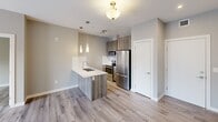 Located at 11235 105 Ave NW in Edmonton, Alberta, this thoughtfully designed 2-bedroom, 2-bathroom unit offers a functional and modern living experience across a single floor. The open-concept living, dining, and kitchen area forms the heart of the space, finished with light-toned hardwood flooring and neutral grey walls that create a clean, contemporary aesthetic. The kitchen is a standout feature, equipped with stainless steel appliances including a refrigerator, stove, and built-in microwave, complemented by wood-toned cabinetry, a white quartz peninsula with an undermount sink, a subway tile backsplash, and stylish pendant lighting. A large window in the living area allows natural light to fill the space, offering views of the surrounding neighbourhood. Both bedrooms are comfortably sized with hardwood flooring, neutral walls, and ample closet space. The primary bedroom includes a dedicated closet, while a second bedroom features a window with natural light. Two full bathrooms serve the unit, one including a soaker tub and tiled surround. A dedicated in-unit laundry area with a stacked washer and dryer adds everyday convenience. Three closets provide generous additional storage throughout.