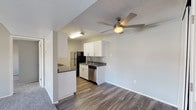 This single-floor residence offers a practical and comfortable layout designed for everyday living. The living area is generously sized, featuring plush carpet flooring, neutral gray walls, and a large front-facing window that fills the space with natural light and views of the surrounding greenery. A ceiling fan overhead adds both comfort and airflow to the open area. The living space flows seamlessly into the dining and kitchen zone, where durable wood-look flooring transitions underfoot. The kitchen is well-equipped with white cabinetry, dark granite-style countertops, and a full suite of appliances including a black refrigerator, electric range, stainless steel dishwasher, and a sink with ample counter space. A pass-through peninsula connects the kitchen to the dining area, enhancing the open feel. The bedrooms are carpeted and spacious, each featuring neutral tones and access to natural light through well-placed windows. One bedroom provides direct access to a bathroom, offering added convenience. The bathrooms are clean and functional, finished with wood-look flooring, white tiled tub-shower combinations, and updated fixtures. A textured ceiling is present throughout, lending a consistent finish to the entire space.