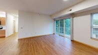 Located at 3020 University Ave SE in Minneapolis, MN, this two-bedroom, one-bathroom residence is thoughtfully laid out on a single floor, providing a comfortable and functional living environment. The open-concept kitchen and living area serves as the heart of the home, featuring warm hardwood-style flooring, recessed lighting, and sliding glass doors that open onto a private balcony with lush tree views. The kitchen is well-appointed with rich honey-toned wood cabinetry, white countertops, a central island with a curved breakfast bar, and a full suite of stainless steel appliances including a French door refrigerator, electric range, microwave, and dishwasher. The spacious living room benefits from abundant natural light streaming through the large sliding doors. Both bedrooms are carpeted and include natural light from windows with blinds; the primary bedroom features hardwood-style flooring and a wood-framed closet door, while the second bedroom is fitted with a built-in double closet with light wood bi-fold doors. An in-unit washer and dryer is also accessible. The bathroom is finished with neutral stone-look tile on the floors and walls, a combined tub and shower, a wood-vanity with white countertop, and a large mirror. Warm wood trim accents are consistent throughout the home, creating a cohesive and inviting aesthetic.