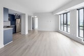 Located at 3385 Dundas St W in Toronto's Junction neighbourhood, this well-appointed 2-bedroom, 2-bathroom unit offers a clean, contemporary design throughout. Light-toned hardwood flooring flows seamlessly across the entire space, complementing the neutral white and warm beige walls that create a bright, airy atmosphere.

The open living area is a standout, featuring large black-framed floor-to-ceiling windows that flood the space with natural light and offer sweeping outdoor views of the Toronto skyline and surrounding greenery. The kitchen is outfitted with modern grey cabinetry, white quartz countertops, a sleek subway tile backsplash, and a full suite of stainless steel Samsung appliances including a range, over-the-range microwave, and refrigerator.

The spacious primary bedroom benefits from generous window coverage, bringing in ample sunlight and outdoor views. The second bedroom is equally well-lit with its own large windows. Both bathrooms feature a consistent modern aesthetic, with light-blue vanity cabinetry, white quartz counters, large-format tile flooring, and a full soaker tub with tiled surround. A hallway connects all rooms efficiently, completing this thoughtfully designed urban residence.