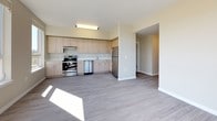 This single-floor unit features a contemporary design with a neutral warm-beige palette and durable grey wood-plank flooring throughout the main living areas. The open-concept living and kitchen space is well-lit, benefiting from multiple large windows and a glass-paneled door that opens to a private balcony overlooking a lush, tree-lined setting. The kitchen is outfitted with light wood laminate cabinetry extending to the upper walls, white quartz countertops, stainless steel appliances including a refrigerator, range, and dishwasher, and an under-mount sink. The layout flows openly between the kitchen and living area, providing a functional and spacious feel.

The bedrooms are carpeted and finished in the same warm-neutral tones, each featuring windows that allow abundant natural light and views of the surrounding neighborhood and greenery. The rooms offer generous proportions suitable for various furniture configurations.

Two full bathrooms serve the unit. One features a dark-countered vanity with wood-grain cabinetry, a large mirror, and a tub-shower combination. The second bathroom is finished in crisp white with light tile flooring and a full tub-shower surround, providing a clean and functional space. Overall, the unit presents a bright, move-in ready environment with modern finishes throughout.
