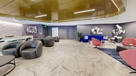 Located in the heart of downtown Los Angeles, this sophisticated clubhouse at 821 S Hope St spans a generously sized single floor, offering residents a premium amenity experience across two distinct zones. The main lounge area immediately impresses with expansive marble-look tile flooring accented by dramatic veining, soaring ceilings, and a striking curved gold-paneled ceiling feature that anchors the space. Seating arrangements blend vibrant cobalt blue sofas, coral-pink swivel chairs, and sculpted gray leather armchairs, creating an eclectic yet cohesive aesthetic. Curated contemporary artwork adorns the walls throughout, adding cultural character to the space. A backlit marble wet bar with bar stool seating provides an elegant entertaining focal point. Large sliding glass doors open to an adjacent game area featuring a ping pong table and access to an outdoor terrace, seamlessly connecting indoor and outdoor living. The private screening room offers a true cinematic experience, complete with a ceiling-mounted projector, a large projection screen, surround sound speakers, tiered rows of plush deep-blue sectional sofas, gold-accented side tables, and acoustically treated walls with vertical illuminated panels. Hexagonal-patterned carpet and a dark ceiling enhance the immersive atmosphere of this exceptional entertainment venue.