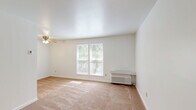Located at 821-831 Sleepy Hollow Road in Pittsburgh, PA, this one-bedroom, one-bathroom unit offers a practical and comfortable single-floor layout. The combined living and dining area is bright and open, featuring wall-to-wall carpeting, a ceiling fan with light fixture, and a wall-unit HVAC system. Natural light filters in through multiple windows with blinds, offering views of surrounding greenery. The entry door opens directly into this versatile living space, which connects seamlessly to the kitchen. The kitchen is well-equipped with white shaker-style cabinetry, granite-look countertops, a double-basin sink, and white appliances including an electric range and refrigerator, all set over warm hardwood-style flooring. The bedroom is a comfortable, carpeted retreat featuring a large double-door closet, a ceiling fan, and a window that brings in natural light. An additional closet provides extra storage in the unit. The bathroom is clean and functional, featuring a full tub-shower combination with built-in shelving and brushed nickel fixtures, complemented by hardwood-style flooring. A hallway connects the main living areas, completing this efficiently designed and move-in-ready home.