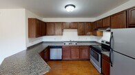Located at 741 S Victory Dr in Mankato, Minnesota, this single-floor unit offers a practical and comfortable layout designed for everyday living. The kitchen serves as a functional centerpiece, featuring rich dark wood cabinetry, granite-style countertops, hardwood flooring, and stainless steel appliances including a dishwasher and electric range — providing ample storage and workspace for cooking. The open layout connects seamlessly to the living areas, which are finished with warm, neutral-toned carpeting and natural light streaming through wood-trimmed windows fitted with blinds. The bedrooms continue the warm aesthetic with plush carpeting, wood-trimmed windows, and closet space, offering a quiet and comfortable retreat. Two bathrooms serve the unit: one features a white vanity with a framed mirror, wood cabinetry, and a lighted vanity bar, while the second offers a similarly clean and functional design with tile flooring, a white vanity, and wood-toned storage. Throughout the unit, warm wood trim accents the baseboards, doors, and window frames, lending a cohesive and inviting character to the space. The neutral color palette and well-maintained finishes make this a versatile and move-in-ready home in Mankato.