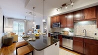 Located in Houston's vibrant Montrose neighborhood, this well-appointed one-bedroom, one-bathroom residence on Dunlavy Street offers a thoughtfully designed single-floor layout that maximizes every square foot. The open-concept kitchen and living area serves as the heart of the home, anchored by rich dark-wood cabinetry that extends to the ceiling, providing ample storage. Dark granite countertops and a mosaic tile backsplash add a polished finish, while a full suite of stainless steel appliances — including a gas range, built-in microwave, dishwasher, and French door refrigerator — elevates the kitchen's functionality. A breakfast bar with seating transitions seamlessly into the living area, which features warm hardwood flooring, track lighting, and a ceiling fan. Sliding glass doors flood the living space with natural light and open to a private balcony with outdoor views. The bedroom offers a serene retreat with plush carpet, a ceiling fan, large windows with greenery views, and generous closet space. The bathroom is finished with neutral tile and includes a soaking tub and shower combination. Throughout the residence, neutral tones and clean lines create a calm, cohesive ambiance ideal for modern urban living.
