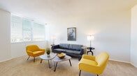 Located on West Franklin Street in Richmond, Virginia, this single-floor residence offers a thoughtfully arranged layout with distinct living, dining, sleeping, and kitchen areas. The living room is bright and welcoming, featuring large windows fitted with horizontal blinds that allow generous natural light to fill the carpeted space. The room comfortably accommodates a seating arrangement and wall art, contributing to a clean, contemporary aesthetic.

Adjacent to the living area, the dining space transitions to hardwood-style flooring and features a ceiling fan with lighting, a dining table with seating for several guests, and an additional window overlooking the surroundings. The kitchen is equipped with warm wood cabinetry, granite-style countertops, a gas cooktop, and black appliances including a refrigerator and dishwasher, all set on tile flooring.

The two bedrooms are carpeted and well-lit, with the primary bedroom featuring expansive floor-to-ceiling windows that draw in abundant natural light. Both rooms offer ample space and include closet access. The bathrooms are finished with classic patterned tile flooring, dark vanity cabinetry, and tub-shower combinations, maintaining a clean and functional design throughout.