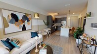 This 1-bedroom, 1-bathroom residence is thoughtfully designed with a modern aesthetic and an efficient open-concept layout. Light-toned hardwood-style flooring flows throughout the main living areas, creating a cohesive and airy feel. The living room features a distinctive horizontally striped accent wall in neutral tones, a ceiling fan, and large windows with a glass door that invite ample natural light and provide outdoor views. The kitchen is a standout feature, equipped with dark wood-grain cabinetry, stainless steel appliances including a French door refrigerator, range, and microwave, as well as crisp white countertops. A central island with an undermount sink, pendant lighting, and bar seating makes it ideal for both cooking and casual dining. A small dining area sits adjacent to the living space, completing the open floor plan. The bedroom is a comfortable retreat with plush carpeting, a ceiling fan, and a large window that frames outdoor greenery. The full bathroom offers a clean, contemporary finish with a tub-shower combo featuring subway tile surround, dark wood vanity cabinetry, and light wood-style flooring. In-unit laundry is also included, adding everyday convenience to this well-rounded residence.