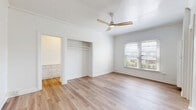 Located at 1800 El Cerrito Place in the desirable Los Feliz neighborhood of Los Angeles, this one-bedroom, one-bathroom unit offers a thoughtfully organized single-floor layout. The spacious primary bedroom features light hardwood-style flooring, crown molding, a ceiling fan with integrated lighting, a built-in closet, and a window that brings in natural light with views of surrounding greenery. A charming arched doorway connects the bedroom to the hallway, adding a distinctive architectural detail that enhances the unit's classic character. The kitchen is a standout with its retro-inspired black-and-white diamond tile backsplash, white cabinetry offering ample storage both above and below the counters, a built-in sink, and black appliances including a gas range and refrigerator. Light ceramic tile flooring completes the kitchen's clean, vintage aesthetic. The bathroom maintains a bright, all-white palette with tile flooring, a combination shower and soaking tub with a frosted window above for natural light and privacy, a pedestal sink, and a built-in dresser providing additional storage. A connecting hallway ties all rooms together efficiently, making the most of the unit's compact yet functional footprint.