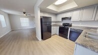 This 700 square foot apartment in Saint Petersburg, Florida, offers a compact yet functional living space with three bedrooms and one bathroom. The unit features a modern design with a mix of flooring types, including hardwood-style floors in the main living areas and kitchen, and plush carpeting in the bedrooms.

The kitchen is equipped with contemporary white cabinets, providing ample storage space. Granite-look countertops complement the cabinetry, and black appliances, including a range and dishwasher, complete the functional cooking space. A tray ceiling adds visual interest above.

The bathroom showcases a clean, white design with a combination tub and shower, surrounded by a white surround with built-in shelving. A single vanity with a granite-look countertop provides storage and grooming space.

The living area is bright and open, featuring ceiling fans for improved air circulation. Windows with vertical blinds allow for natural light and privacy control. The bedrooms, while compact, offer closet space with sliding doors.

Throughout the apartment, neutral wall colors create a blank canvas for personalizing the space. The overall layout, as seen in the 3D floor plan, maximizes the use of the available square footage, making this unit an efficient and modern living option in the Waterside Village complex.