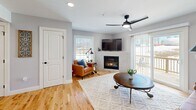 This contemporary townhouse in Laconia, NH offers 910 square feet of thoughtfully designed living space across three floors. The main level showcases a modern kitchen with sleek gray cabinetry, stainless steel appliances, and a subway tile backsplash. The adjacent living room features hardwood floors, a cozy fireplace, and large windows that flood the space with natural light. The primary bedroom, measuring 140 square feet, boasts ample space and outdoor views. A second bedroom and a well-appointed bathroom complete the upper level. The ground floor includes a spacious garage with concrete flooring and built-in storage solutions. Throughout the home, modern fixtures like ceiling fans and recessed lighting enhance the contemporary ambiance. The property's neutral color palette and clean lines create a fresh, inviting atmosphere, while strategic placement of windows offers picturesque views of the surrounding area, seamlessly blending indoor comfort with outdoor beauty.