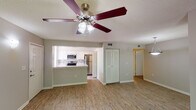 This single-floor residence offers a thoughtfully designed layout that balances comfort and functionality. The open-concept living and dining areas are finished with warm wood-look flooring, neutral gray walls, and textured ceilings, creating a bright and welcoming atmosphere. Ceiling fans are present throughout the main living spaces, providing both style and practicality. Large windows and sliding glass doors flood the interior with natural light while offering views of the surrounding greenery.

The kitchen is a standout feature, boasting white shaker-style cabinetry, a classic tile backsplash, and a full suite of stainless steel appliances including a range, microwave, and refrigerator. A peninsula with a light stone countertop and an integrated sink serves as both a functional workspace and a casual dining area, seamlessly connecting the kitchen to the living space.

The bedrooms are carpeted for comfort and include ceiling fans, louvered closet doors offering ample storage, and access to natural light. The primary bedroom connects directly to a well-lit bathroom featuring a wide double-sink vanity with a light stone countertop, white cabinetry, and a large mirror with an illuminated fixture above. The overall design is clean and move-in ready, with a neutral palette that suits a variety of furnishing styles.
