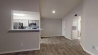 This single-story, 2-bedroom, 2-bathroom home offers a thoughtfully designed layout with consistent wood-look flooring running throughout every room. The open-concept living area is a standout feature, boasting vaulted ceilings that lend a sense of spaciousness, a ceiling fan with integrated lighting, and a tiled fireplace as a focal point. A window allows natural light to fill the room, while neutral gray walls create a clean, modern palette.

The kitchen is accessible via a pass-through counter that opens to the living space, offering a breakfast bar configuration. Inside, gray cabinetry with modern hardware lines both sides of the galley-style layout, complemented by white countertops, a stainless steel sink, black appliances including a refrigerator and range, and a tiled backsplash.

Both bedrooms are generously proportioned, each featuring ceiling fans and closet space. The hallway connects the bedrooms and provides access to both bathrooms. Each bathroom includes gray vanity cabinetry, white countertops, a framed mirror, and a tub-shower combination with white tile surround. The overall aesthetic is cohesive, modern, and move-in ready.