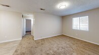 Located in Covington, GA, this single-floor residence offers a practical and comfortable layout designed for efficient everyday living. The galley-style kitchen is outfitted with white cabinetry, light stone-finish countertops, a stainless steel sink, and a full suite of white appliances including a range, microwave, and refrigerator — all set atop wood-look tile flooring that lends a clean, modern feel. The spacious bedroom features soft wall-to-wall carpeting, a ceiling fan with light fixture, a natural window bringing in ambient outdoor light, and a closet with bifold doors offering generous storage. The full bathroom includes a tub-shower combination with a safety grab bar, wood-look tile flooring, and a vanity with countertop storage. Neutral warm-beige tones throughout the space, paired with white trim and textured ceilings, create a bright and cohesive atmosphere. The overall layout, as seen in the 3D overview, flows logically from the kitchen through the living areas to the private bedroom and bath, making this a well-organized and move-in-ready residence.
