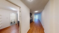Located at 110 W 39th Street in Baltimore, MD, this single-floor residence offers a thoughtfully designed layout with a seamless flow between living spaces. Warm hardwood flooring extends throughout the main areas, complemented by clean white walls and textured ceilings that add character to each room.

The open living area is a standout feature, anchored by a large floor-to-ceiling window with vertical blinds that invite abundant natural light and offer views of the surrounding greenery. The spacious layout provides versatile room for a variety of furniture arrangements.

The kitchen is equipped with dark espresso-toned cabinetry, granite-patterned countertops, stainless steel appliances including a gas range and dishwasher, and a built-in microwave hood — offering both functionality and a modern aesthetic.

The bathroom is designed with practicality in mind, featuring a combined tub and shower with tiled surround, brushed nickel fixtures, and a separate vanity area with a wide mirror, built-in shelving, and dark cabinetry with ample storage. The toilet compartment is neatly separated for added privacy. Blue-grey tile flooring in the bathroom provides a clean, classic finish.

A connecting hallway ties the rooms together efficiently, creating a cohesive and functional living environment throughout.