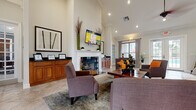 Located at 105 Brookhaven Ct N in Palm Coast, Florida, this single-floor space offers a thoughtfully designed layout encompassing a living room, dining area, kitchen, and a dedicated office. The living room is a standout feature, boasting soaring vaulted ceilings with crown molding, recessed lighting, and a ceiling fan. A classic white fireplace serves as the room's focal point, flanked by warm wood cabinetry and complemented by large-format tile flooring. French doors and expansive windows allow abundant natural light to flow throughout, creating a bright and welcoming ambiance. The open-concept design connects the living area seamlessly to the dining space, which features a round glass-top dining table and direct views to the outdoors. A pass-through counter with decorative wood corbels links the main area to the kitchen, which is equipped with rich wood cabinetry, dark granite countertops, and a tile backsplash. The dedicated office is carpeted and well-lit by multiple windows, offering a quiet and functional workspace. The entry foyer makes a strong first impression with its high ceiling, tile flooring, and elegant French doors leading further into the space. Overall, the design balances practicality with refined detail throughout.
