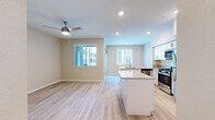 This thoughtfully designed single-floor residence offers a clean, modern aesthetic throughout its efficient layout. The open-concept kitchen and living area forms the heart of the home, featuring light hardwood-style flooring, recessed lighting, and a ceiling fan that enhances airflow and comfort. The kitchen is well-appointed with white shaker-style cabinetry, light quartz countertops, a full suite of stainless steel appliances including a gas range, built-in microwave, dishwasher, and refrigerator, and a functional island with a sink that doubles as a breakfast bar. Multiple windows invite natural light into the living area, creating a bright and airy atmosphere. The bedroom offers plush carpeting, a ceiling fan, and a window with natural light, complemented by a walk-in closet equipped with wire shelving for organized storage. Two full bathrooms serve the residence, each featuring white shaker vanity cabinetry, quartz countertops, and a tub-shower combination with clean tile surrounds. A hallway connects the private areas of the home, contributing to a logical and comfortable flow. The neutral color palette throughout lends the space a fresh, move-in-ready appeal.