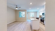 This thoughtfully designed single-floor residence offers a clean, modern aesthetic throughout its efficient layout. The open-concept kitchen and living area forms the heart of the home, featuring light hardwood-style flooring, recessed lighting, and a ceiling fan that enhances airflow and comfort. The kitchen is well-appointed with white shaker-style cabinetry, light quartz countertops, a full suite of stainless steel appliances including a gas range, built-in microwave, dishwasher, and refrigerator, and a functional island with a sink that doubles as a breakfast bar. Multiple windows invite natural light into the living area, creating a bright and airy atmosphere. The bedroom offers plush carpeting, a ceiling fan, and a window with natural light, complemented by a walk-in closet equipped with wire shelving for organized storage. Two full bathrooms serve the residence, each featuring white shaker vanity cabinetry, quartz countertops, and a tub-shower combination with clean tile surrounds. A hallway connects the private areas of the home, contributing to a logical and comfortable flow. The neutral color palette throughout lends the space a fresh, move-in-ready appeal.