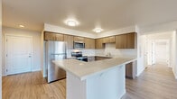 Located at 256 Prince Ave in Bellingham, WA, this well-appointed 3-bedroom, 2-bathroom residence offers a thoughtfully designed single-level layout. The open-concept kitchen and living area serves as the heart of the home, featuring warm wood-toned cabinetry, a large quartz-topped island, stainless steel appliances including a refrigerator, range, and microwave, and ample counter space. The kitchen flows seamlessly into the bright living room, which is finished with light luxury vinyl plank flooring and benefits from generous natural light through large windows and a sliding glass door that opens to a private balcony with neighborhood views. The three bedrooms are comfortably sized, with the primary bedroom offering notable square footage, and each room features neutral walls, vinyl plank flooring, and sliding closet doors. The two bathrooms are finished with stone-look tile flooring. The full bathroom includes a soaking tub and shower combo, while the second bathroom features a long vanity with wood cabinetry and a large mirror. A dedicated hallway connects all rooms efficiently. The overall aesthetic is clean, modern, and move-in ready, with a consistent neutral palette throughout.