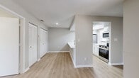 Located at 7610 W Waters Ave in Tampa, Florida, this single-story, one-bedroom, one-bathroom unit offers a clean, modern aesthetic throughout its efficiently designed floor plan. The open-concept kitchen serves as a functional centerpiece, featuring stainless steel appliances including a refrigerator, gas range, and built-in microwave. A skylit tray ceiling above the kitchen adds an architectural flourish while drawing in natural light, complementing the bright white cabinetry, subway tile backsplash, and expansive light-toned quartz countertop with an integrated sink. The living area flows seamlessly from the kitchen, finished with warm wood-look laminate flooring that extends throughout the unit, creating a cohesive and inviting atmosphere. The bedroom is a generously sized retreat, complete with a ceiling fan and light fixture, neutral-toned walls, and continued laminate flooring. It connects to a dedicated walk-in closet outfitted with dual wire shelving systems on both sides, offering ample organization and storage. The bathroom is clean and functional, featuring a white vanity with quartz countertop, a full tub-shower combination with white tile surround, and matching laminate flooring. The overall design palette of soft grays, whites, and warm wood tones gives the unit a cohesive, contemporary feel.