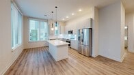 Located at 222 N West St in downtown Raleigh, NC, this well-designed 2-bedroom, 1-bathroom residence offers a thoughtful layout across a single floor. The open-concept living area seamlessly integrates the kitchen, dining, and living spaces, creating a bright and functional hub for everyday living. The kitchen is outfitted with stainless steel appliances — including a refrigerator, range, microwave, and dishwasher — complemented by sleek white quartz countertops, a subway tile backsplash, and ample cabinetry. A central island provides additional prep and storage space, illuminated by stylish globe pendant lights. Large windows throughout the unit allow natural light to fill each room, with views of the surrounding Raleigh cityscape. Light wood-style flooring runs continuously throughout the unit, enhancing the clean, modern aesthetic. The spacious primary bedroom features a ceiling fan and generous closet space, while the second bedroom also benefits from large windows and its own closet. The bathroom is finished with a subway tile tub surround, a white vanity, and wood-style flooring. Additional spaces include a hallway, laundry area, utility room, and two closets, ensuring practical storage and convenience throughout.