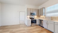 This contemporary two-story home is thoughtfully designed with clean lines, a neutral palette, and high-quality finishes throughout. The kitchen is a standout feature, outfitted with grey flat-front cabinetry, light stone countertops, a tasteful tile backsplash, and a full suite of stainless steel appliances including a range, microwave, dishwasher, and refrigerator. Light hardwood flooring runs throughout the main living areas, lending warmth and continuity to the open layout.

The living and dining areas are bright and airy, benefiting from generous natural light and tall ceilings that enhance the sense of space. Multiple rooms feature large windows dressed with horizontal blinds, offering neighborhood views while maintaining privacy. Ceiling fans are present in select rooms, adding comfort and functionality.

The bedrooms offer a peaceful retreat, with plush wall-to-wall carpeting in some rooms and hardwood flooring in others, all bathed in natural light from multi-pane windows. The bathroom is well-appointed, featuring a glass-enclosed walk-in shower, a grey vanity with light countertops, and a tall window that invites natural light. A staircase connects the two levels, completing the practical and well-organized floor plan of this move-in-ready home.