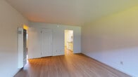 Located at 1201 Liberty St in El Cerrito, California, this single-floor residence offers a clean, functional layout designed for comfortable living. The main living area features light hardwood-style flooring that extends throughout the common spaces, creating a bright and cohesive feel. A large window with a window shade allows natural light to fill the room, while a wall-mounted HVAC unit provides climate control. The galley-style kitchen is efficiently designed with white cabinetry, dark granite-style countertops, a sink, and white appliances including an electric range and refrigerator. The kitchen opens directly into the living area, promoting an easy flow between spaces. The bedrooms are carpeted for added comfort and each features windows that bring in natural light and views of the surrounding neighborhood. One bedroom includes a spacious sliding-door closet with built-in shelving and hanging rods, offering ample storage. The bathroom is appointed with a full tub and shower combination, framed by classic white tile surround and sliding glass doors. Throughout the unit, neutral wall tones and clean finishes contribute to a straightforward, move-in-ready atmosphere.