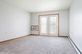 Located at 3125 Pennsylvania Ave in Dubuque, Iowa, this one-bedroom, one-bathroom unit offers a practical and comfortable single-floor layout. The galley-style kitchen is well-equipped with stainless steel appliances, including a refrigerator, dishwasher, and range, complemented by rich brown cabinetry, light stone-toned countertops, and durable light wood vinyl flooring. A pass-through window connects the kitchen to the adjoining living area, enhancing the open feel between spaces. The living room features soft wall-to-wall carpeting, a wall-mounted air conditioning unit, and a set of French doors that allow natural light to fill the room while providing outdoor access. A ceiling fan adds comfort to the bedroom, which is carpeted and includes a full-width wooden bi-fold closet, offering ample storage. Natural light filters in through a window fitted with blinds. The bathroom is finished with the same light vinyl flooring as the kitchen, and includes a vanity with brown cabinetry, a tub-shower combination, and a baseboard heater. A hallway connects the main living areas, with warm wood-toned doors providing a cohesive design detail throughout. Baseboard heating is present in multiple rooms, ensuring year-round comfort in this well-maintained unit.