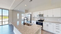 Located at 5700 Crossings Blvd in Nashville, TN, this two-story home offers a thoughtfully designed layout across two well-proportioned floors. The main level features an open-concept kitchen and living area, anchored by a striking floor-to-ceiling grid window that floods the space with natural light and offers views of the surrounding neighborhood. The kitchen is appointed with crisp white cabinetry, granite countertops, a large center island with a double sink, and a full suite of stainless steel appliances. Hardwood-style flooring runs throughout the main level, complementing the clean, contemporary aesthetic. Upstairs, the second floor houses both bedrooms, two full bathrooms, a closet, and staircase access. The bedrooms feature plush carpeting, ceiling fans, and windows that bring in natural light. The primary bathroom includes a soaking tub and direct access to a dedicated closet with built-in shelving. A second staircase adds convenience and connectivity between the floors. Neutral warm-toned walls, black hardware accents, and consistent modern finishes tie the entire home together, creating a cohesive and inviting atmosphere throughout.