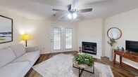 Located at 101 Montrose Ct in Dothan, Alabama, this well-appointed single-story home offers a comfortable and functional layout across two bedrooms, three bathrooms, and two closets. The living room serves as the heart of the home, featuring rich hardwood-style flooring, a ceiling fan, a classic fireplace, and French doors that invite natural light and provide outdoor access. Adjacent to the living area, the dining room is highlighted by an elegant multi-light chandelier and additional hardwood-style flooring, creating a warm and inviting space for meals and gatherings. The galley-style kitchen is equipped with warm wood cabinetry, dark green countertops, white appliances including a range, microwave, dishwasher, and refrigerator, along with a double basin sink. Both bedrooms are carpeted and feature natural light from windows. The primary bedroom includes a ceiling fan and access to a spacious walk-in closet with wire shelving. The bathrooms are fitted with warm wood vanities, white countertops, and tub-shower combinations. One bathroom features wood-look flooring and accessibility grab bars for added convenience. The home's neutral color palette and practical design make it a comfortable and versatile living space.