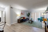 This thoughtfully designed 2-bedroom, 1-bathroom residence offers a comfortable and functional layout across a single floor. The living room serves as the centerpiece of the home, highlighted by a striking white-painted brick fireplace and wood-style plank flooring that extends throughout the main living areas. Sliding glass doors allow natural light to fill the space, creating a bright and welcoming atmosphere. Adjacent to the living room, the dining area provides an intimate setting ideal for everyday meals, also finished with the same warm flooring. The galley-style kitchen is well-equipped with dark cabinetry, granite-style countertops, stainless steel appliances including a refrigerator, electric range, and dishwasher, all complemented by light wood-look tile flooring. A connecting hallway leads to both bedrooms and the shared bathroom, which features matching dark cabinetry and granite-style countertops. The spacious primary bedroom is finished with plush carpeting and includes a generous closet with built-in shelving. The second bedroom, also carpeted, offers ample space and natural light from a large window. Throughout, the neutral color palette and clean finishes provide a cohesive and move-in-ready aesthetic.