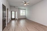 This well-designed single-floor residence offers a thoughtfully laid-out open-concept living space with light hardwood flooring that flows throughout the main areas. The kitchen is a standout feature, equipped with dark espresso cabinetry, granite countertops, a tiled backsplash, and stainless steel appliances including a range, microwave, and refrigerator. A peninsula with pendant lighting and a double stainless steel sink provides both prep space and a casual dining option. The living area benefits from natural light through large windows with blinds, a ceiling fan, and direct access to an outdoor area via a glass door. Two bathrooms serve the residence — one with a walk-in shower and wall-mounted sink, and another featuring a soaking tub/shower combination and matching granite-topped vanity with dark cabinetry. The bedrooms are carpeted for comfort and include built-in closets with wire shelving. A dedicated walk-in closet area adjacent to one bathroom provides generous storage. Neutral gray walls and clean white trim lend the space a crisp, contemporary aesthetic throughout.