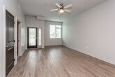 This well-designed single-floor residence offers a thoughtfully laid-out open-concept living space with light hardwood flooring that flows throughout the main areas. The kitchen is a standout feature, equipped with dark espresso cabinetry, granite countertops, a tiled backsplash, and stainless steel appliances including a range, microwave, and refrigerator. A peninsula with pendant lighting and a double stainless steel sink provides both prep space and a casual dining option. The living area benefits from natural light through large windows with blinds, a ceiling fan, and direct access to an outdoor area via a glass door. Two bathrooms serve the residence — one with a walk-in shower and wall-mounted sink, and another featuring a soaking tub/shower combination and matching granite-topped vanity with dark cabinetry. The bedrooms are carpeted for comfort and include built-in closets with wire shelving. A dedicated walk-in closet area adjacent to one bathroom provides generous storage. Neutral gray walls and clean white trim lend the space a crisp, contemporary aesthetic throughout.