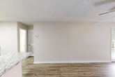 Located at 1159 Harrison Pike in Cleveland, Tennessee, this single-floor, one-bedroom, one-bathroom unit offers a well-organized layout designed for comfortable everyday living. The kitchen is a standout feature, boasting white shaker-style cabinetry, granite countertops, a subway tile backsplash, stainless steel appliances, and a skylight that floods the space with natural light. Wood-look luxury vinyl flooring runs throughout the main living areas, adding warmth and durability. The open living room is bright and neutral, with clean white trim, textured ceilings, and a view toward the bedroom hallway. A louvered pantry door provides accessible storage just off the kitchen. The bedroom is a comfortable size, finished with plush carpet, a window allowing natural light, and direct access to a dedicated walk-in closet with built-in shelving. Additional storage is provided by two closets throughout the unit. A private patio extends the living space outdoors. Neutral wall tones and consistent finishes throughout give the unit a cohesive, move-in-ready appearance. The space includes one full bathroom and benefits from a functional, efficient floor plan suited for single occupants or couples.