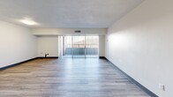 Located at 1100 Penn Center Blvd in Pittsburgh, PA, this single-floor unit offers a straightforward and functional layout designed for comfortable everyday living. The living area is bright and open, featuring light-toned vinyl plank flooring and clean white walls accented by bold dark baseboards. A sliding glass door floods the space with natural light and provides direct access to a private balcony, offering outdoor views of the surrounding area. The textured ceiling and built-in ventilation contribute to the room's practical design.

The kitchen is efficiently laid out with white cabinetry, granite-style countertops, and white appliances including a refrigerator and electric range. Light wood-toned vinyl flooring continues throughout this area, maintaining a cohesive aesthetic. A secondary room, also finished with vinyl plank flooring in a complementary gray tone, offers versatile use and includes a built-in shelf detail along one wall.

The bathroom is finished with full white ceramic tile surrounding a soaking tub and shower combination, complemented by chrome fixtures and a clean, minimalist design. Throughout the unit, the neutral color palette, updated flooring, and consistent finishes create a tidy, move-in-ready environment well-suited for practical, low-maintenance living.