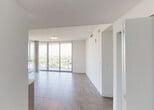 Located at 2900 SW 28th Lane in Miami's desirable Coconut Grove neighborhood, this modern high-rise unit offers a refined living experience defined by clean lines, contemporary finishes, and sweeping panoramic views of the Miami skyline and lush treetop canopy below. Large-format porcelain tile flooring runs throughout, complementing the bright, white walls and creating a cohesive, polished aesthetic.

The open-concept living and dining area is anchored by expansive floor-to-ceiling sliding glass doors that lead to a private balcony, flooding the interior with abundant natural light and providing unobstructed elevated views of the surrounding cityscape. The kitchen is well-appointed with light wood cabinetry, a glass tile backsplash, white quartz countertops, and a full suite of stainless steel appliances including a French door refrigerator, range, built-in microwave, and dishwasher. In-unit washer and dryer hookups offer added convenience.

The bedrooms are generously proportioned, each benefiting from floor-to-ceiling glass doors that frame the striking outdoor views. Ample closet space, including a walk-in closet, adds practical storage. The bathrooms are finished with modern floating vanities, clean white countertops, and large mirrors that enhance the sense of light and space throughout.