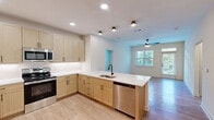 Located at 15576 Voyage Pl in Waldorf, MD, this well-appointed 2-bedroom, 2-bathroom unit offers a thoughtfully designed single-floor layout. The open-concept kitchen is a standout feature, showcasing light wood cabinetry with matte black hardware, crisp white quartz countertops, stainless steel appliances including a refrigerator, range, microwave, and dishwasher, and a peninsula with an undermount sink — ideal for both cooking and casual entertaining. Wood-look luxury flooring runs throughout the kitchen and living areas, lending warmth and continuity to the space. The living area is bright and airy, enhanced by a ceiling fan and natural light from large windows that frame views of surrounding greenery. Both bedrooms are generously sized, carpeted for comfort, and filled with natural light through sizable windows with wooded views. The primary bedroom offers a spacious footprint with direct access to its own bathroom. Both bathrooms are finished with warm wood vanities, white quartz countertops, matte black fixtures, and tub-shower combinations with clean tile surrounds. A dedicated closet and hallway round out the functional layout, making this a comfortable and move-in-ready home.