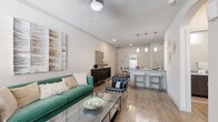 This single-story, 2-bedroom, 1-bathroom residence offers a thoughtfully arranged floor plan that maximizes comfort and functionality. The open-concept living area greets you with wood-look flooring, a ceiling fan, and a large window that fills the space with natural light. The living room flows seamlessly into the combined kitchen and dining area, where pendant lighting illuminates a granite-topped breakfast bar with bar seating. The kitchen is equipped with stainless steel appliances, including a refrigerator and range, complemented by dark cabinetry and ample counter space. A dedicated dining nook provides a cozy setting for meals. The bedrooms feature plush carpeting, ceiling fans, and generous closet space with built-in shelving and hanging rods. The primary bedroom offers a notably comfortable footprint with good natural light from a large window. The shared bathroom is finished with tile-surround tub and shower, wood-look flooring, a granite vanity, and dark wood cabinetry. A dedicated laundry room with a full-size washer and overhead shelving adds everyday convenience. Neutral tones and consistent finishes throughout create a cohesive, modern aesthetic.